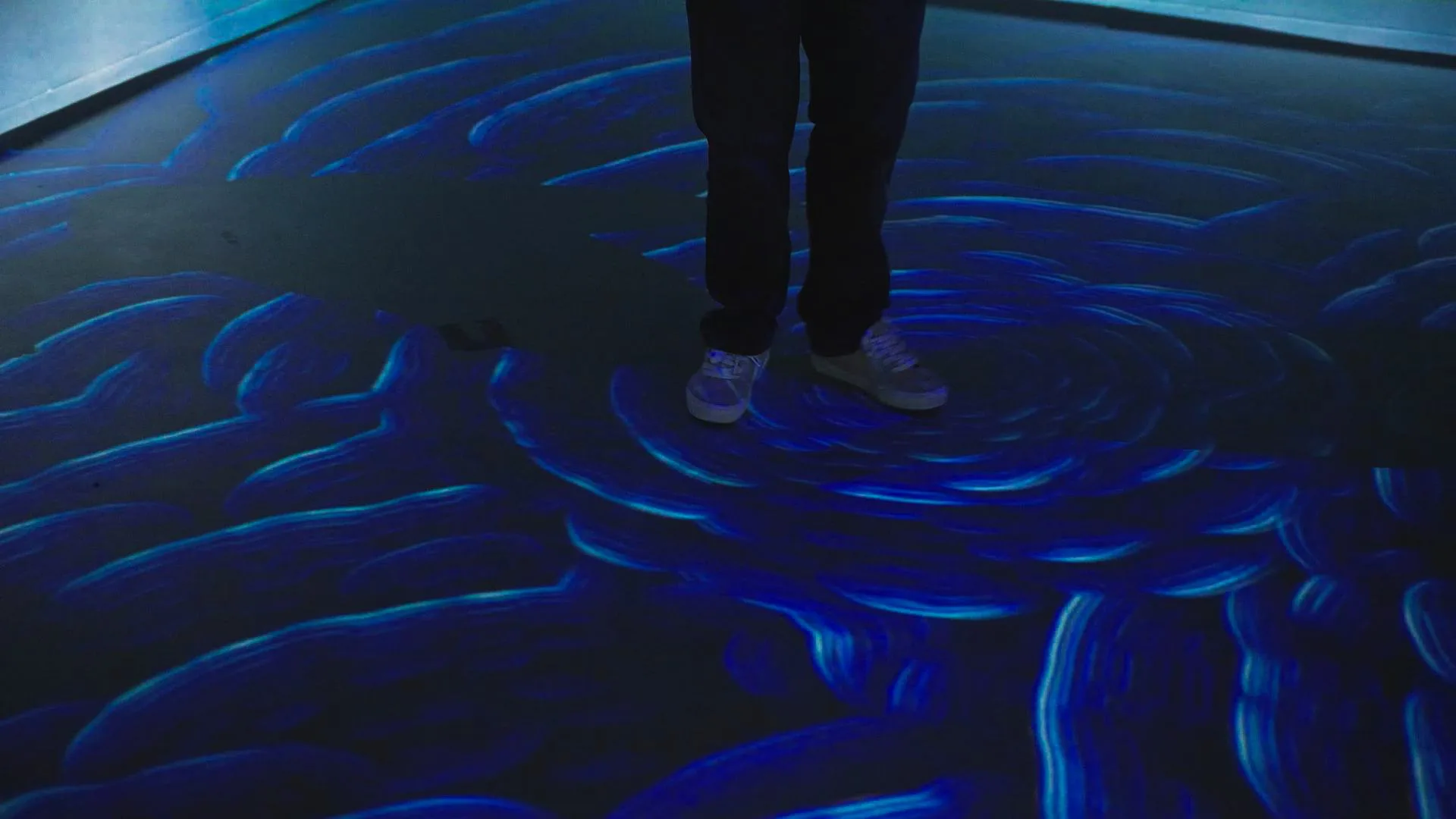 Blue current lines swirling across the floor around a visitor's feet