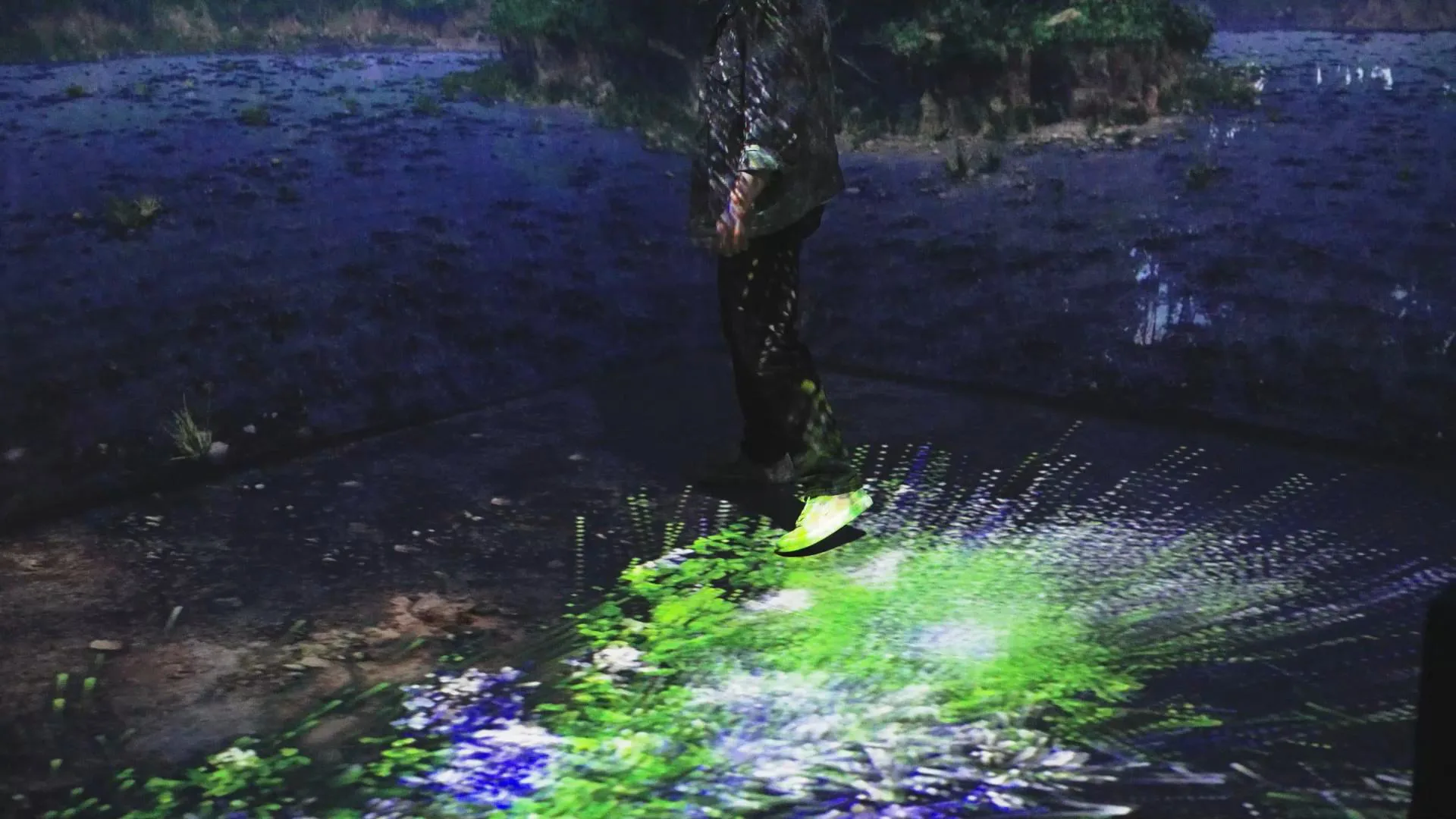 A visitor standing on the projected floor as a burst of green light spreads around them