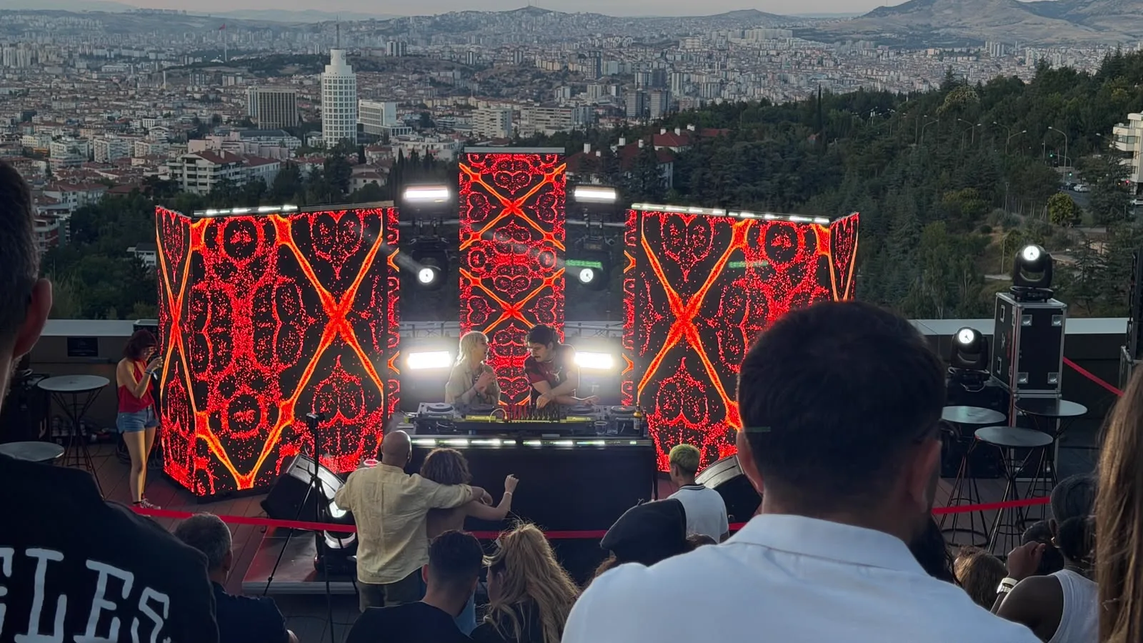 The crowd seated on the grass before the red screens
