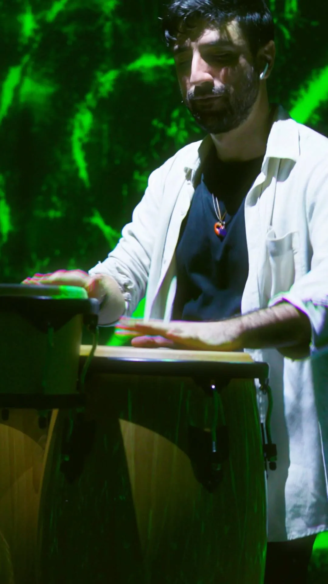 The percussionist playing, the green pattern moving on the wall behind