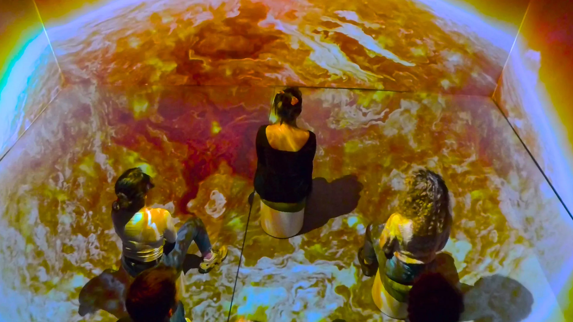 An audience on the surface of the Sun, seen from above, the plasma texture running under their seats
