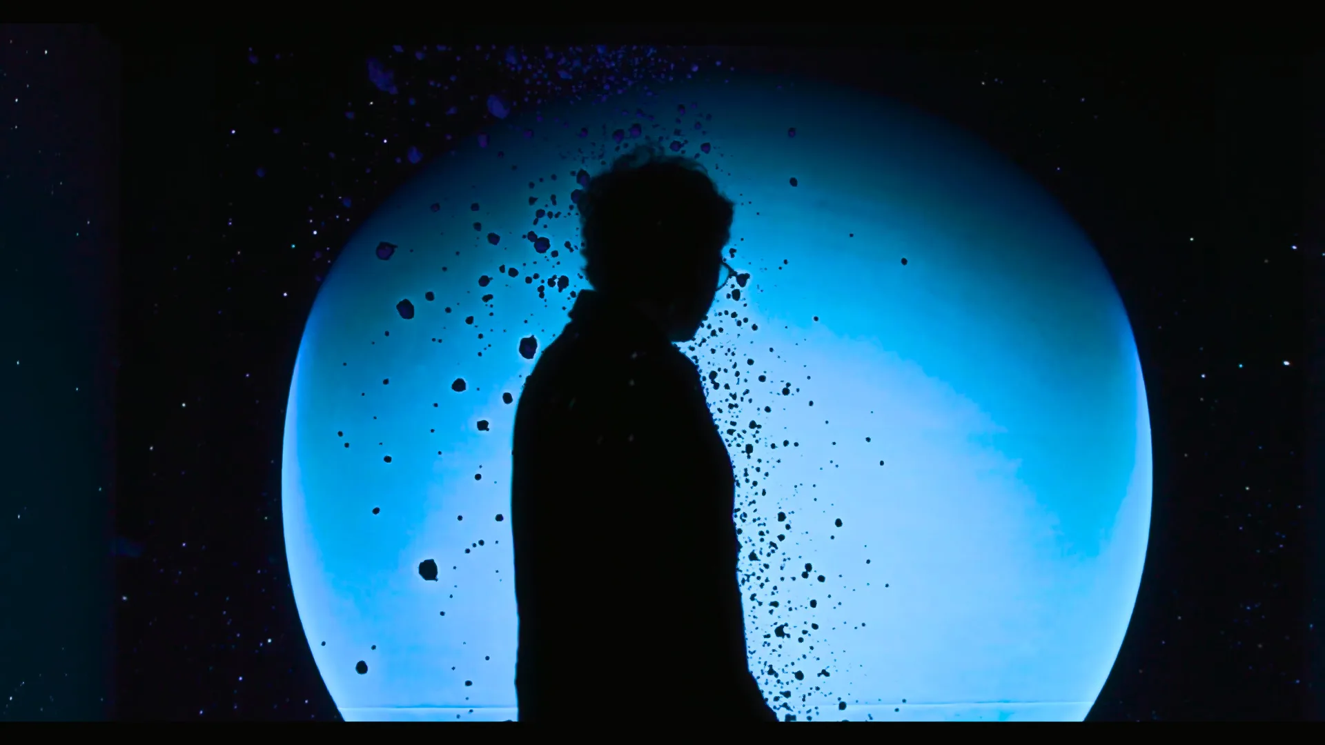 Installed: a visitor silhouetted against the cyan disc of Uranus